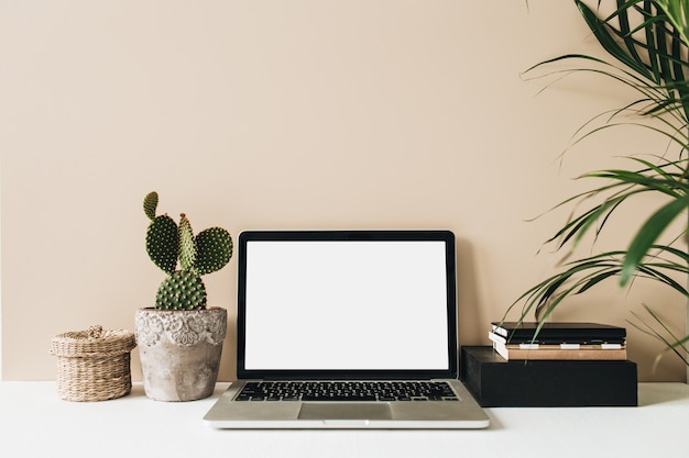 Minimalistische thuiskantoor-werkruimte met laptop, cactus en palm op beige