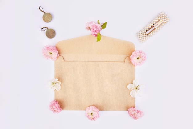 Minimalistische vrouwelijke lente envelop mockup met roze bloemen accessoires haar clip oorbellen op stof witte achtergrond 8 maart concept