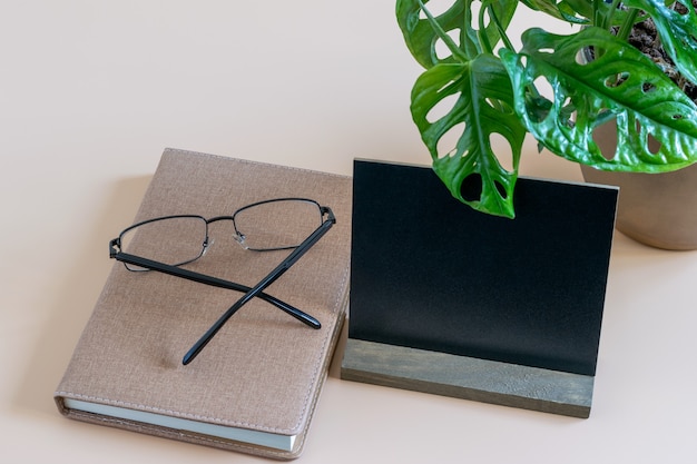 Minimalistische werkplek met tijddagboek, bril met ogen en zwarte blanco. Mockup-foto met ruimte voor uw tekst.