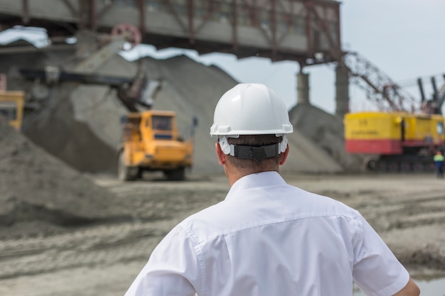 Mining engineer in white shirt and helmet supervises work of granite workshop