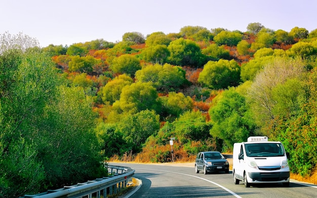 写真 イタリア、サルデーニャ島の地中海のコスタスメラルダで夏にミニバンと車が走っています。高速道路や高速道路での休日のミニバン。ミクストメディア。