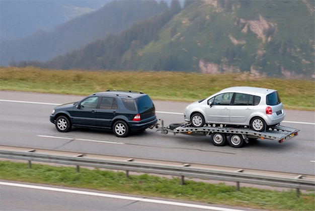 ミニバン バス が フラットベッド で 家族 の 車 を 牽引 し て いる