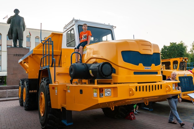 Minsk Belarus JULY 22 2022 Children with fun and joy look at new large cars bulldozers tractors on the stand of new large working equipment Huge Belarusian truck