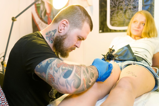 Minsk bielorussia 19 settembre 2015 artista professionista che fa tatuaggio sulla gamba del cliente