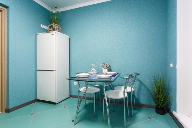 Minsk belarus september 2020 interior of the modern kitchen\
with guest table in studio apartments in minimalistic style with\
turquoise color