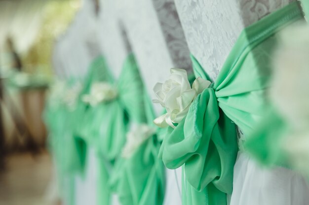 Mint bows and white cloth flowers put on white chairs