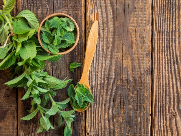 Rami di menta e una ciotola di legno con un mazzo di menta fresca su un tavolo di legno concetto di cibo sano