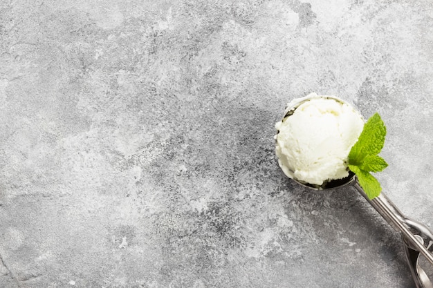 Mint ice cream in spoon on a gray background.