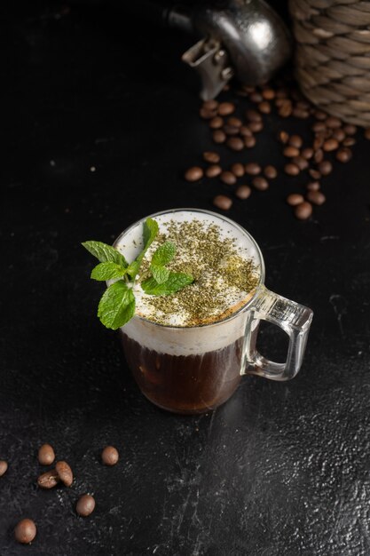 Caffè piccante alla menta con foglie di menta fresca in una tazza trasparente.