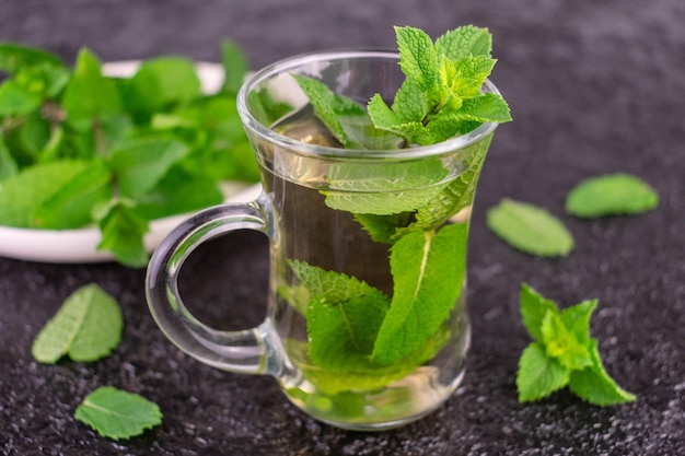 Foto tè alla menta. una tazza di tè alla menta su sfondo nero.