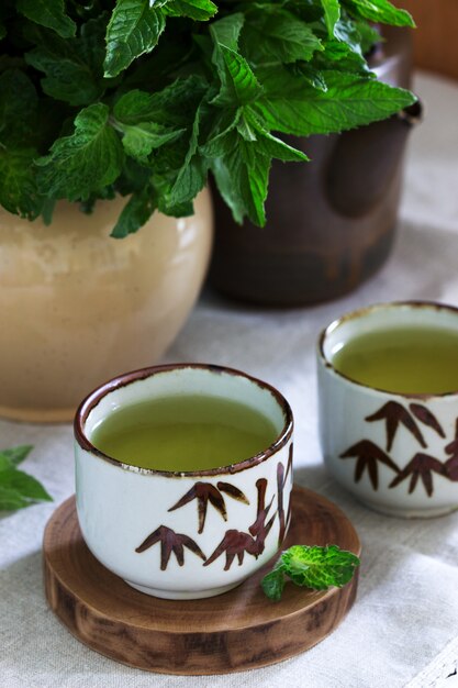 Tè alla menta in un set da tè cinese vintage e un bouquet di menta in una brocca