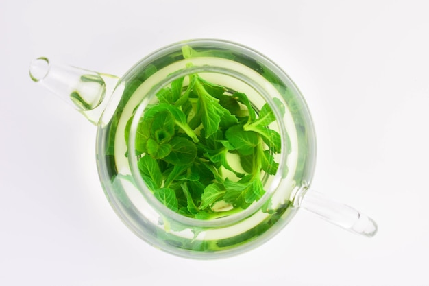 Mint tea with fresh mint leaves in a glass teapot Flat lay