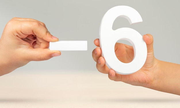 Minus six the number six and the minus symbol in a hand closeup on a light gray background the conce