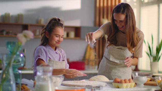 Photo mirl and mother preparing dough for cookies on kitchen