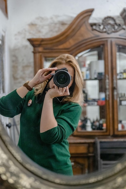 Photo a mirror image of a woman in green sweatshirt using a black camera photo