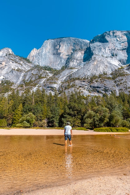 ミラー湖、湖の水と太陽に沿って歩く白いシャツを着た若い男。カリフォルニア、米国