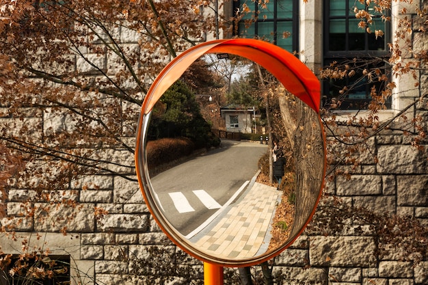 Mirror on the road for visibility. In the reflection, the girl in the autumn park. Close-up. Seoul, South Korea, 01-04-2018.