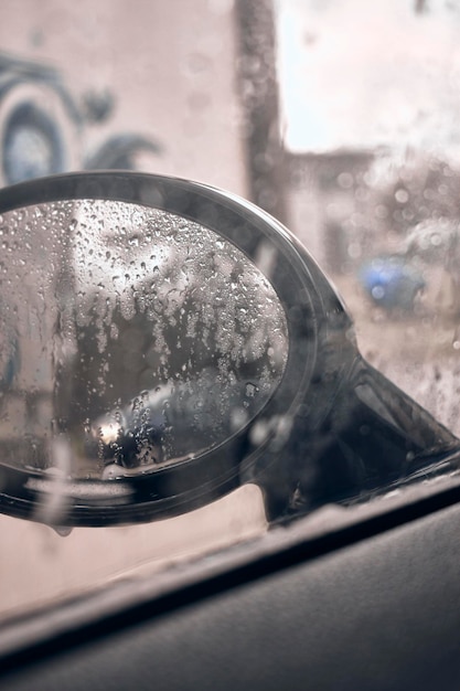 A mirror with water droplets on it and a graffiti on the wall