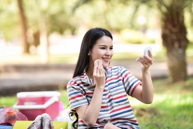 Mirror woman Make up cosmetics smiling young girl make up face on outdoors Powder make up woman look at mirror personally 