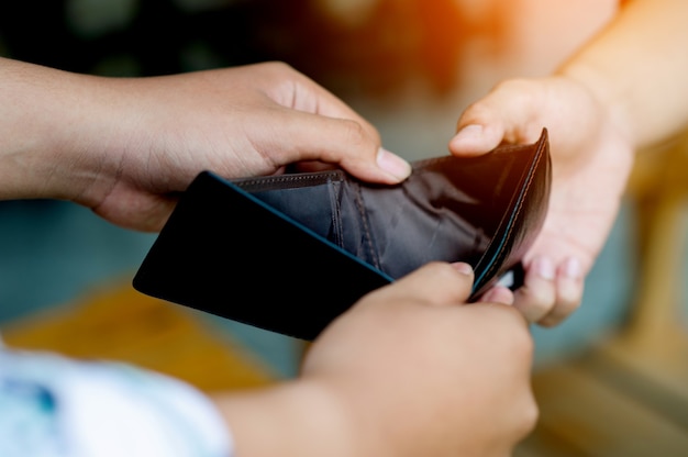 Mislukte financiën, gebrek aan geld, gebrek aan inkomen, werkloosheid, handen en portemonnee, twee mannen met dezelfde portemonnee. Toont gebrek aan inkomen, gebrek aan geld, arbeidsomstandigheden zonder geld.