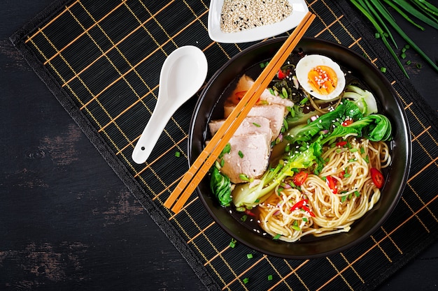 Miso Ramen Asian noodles with egg, pork and pak choi cabbage in bowl. Japanese cuisine. Top view. Flat lay