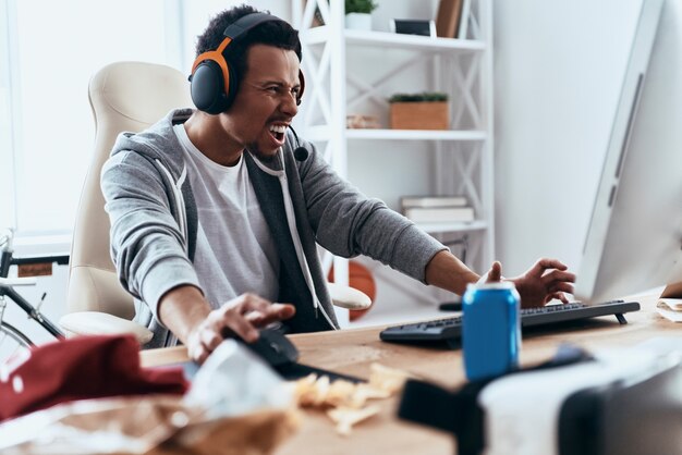 Mission failed. Frustrated young man in casual clothing using computer while spending time at home