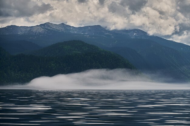 Mist in de ochtendmist van de bergvallei over het meer in het altai-gebergte