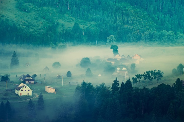 Mistige ochtend berg zomerlandschap met mist en dorp