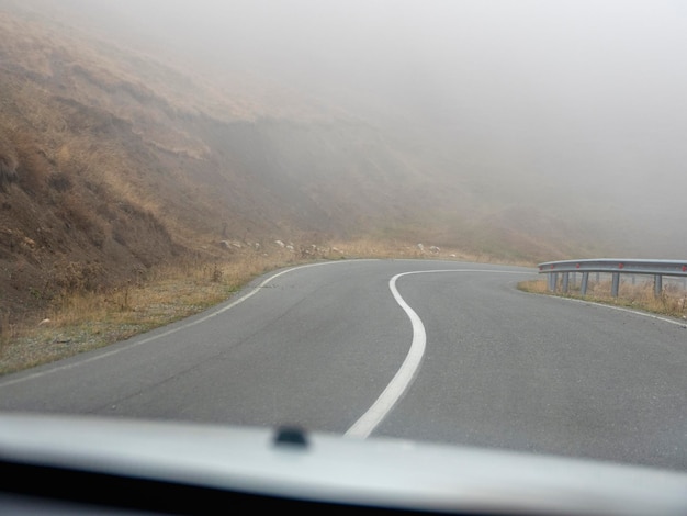 Mistige snelweg Uitzicht vanaf de bestuurder van de auto Lege ochtend berg snelweg in een dichte mist Weg door een dichte mist