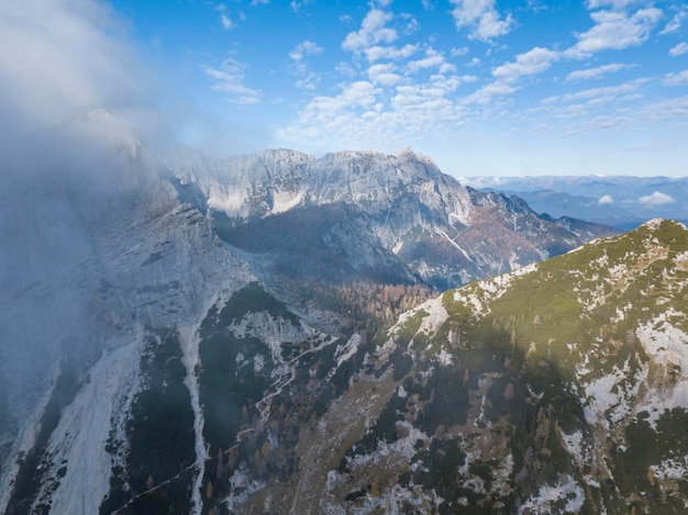 スロベニアのジュリアンアルプスの黄色いカラマツの木がある山道の霧のかかった朝