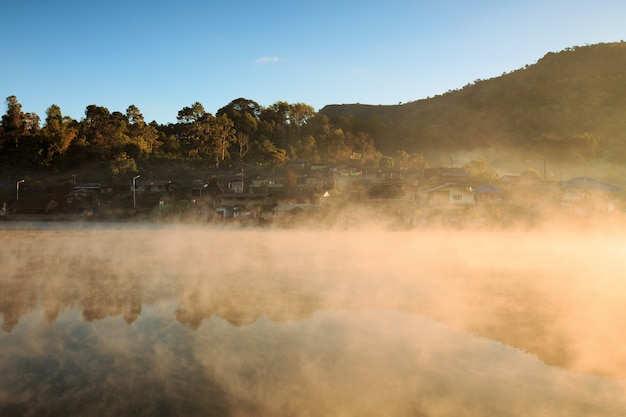 Foto alba nebbiosa mattina sopra la montagna con il villaggio intorno al fiume