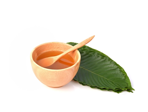 Mitragyna speciosa water in wooden spoon and bowl and leaves on white background