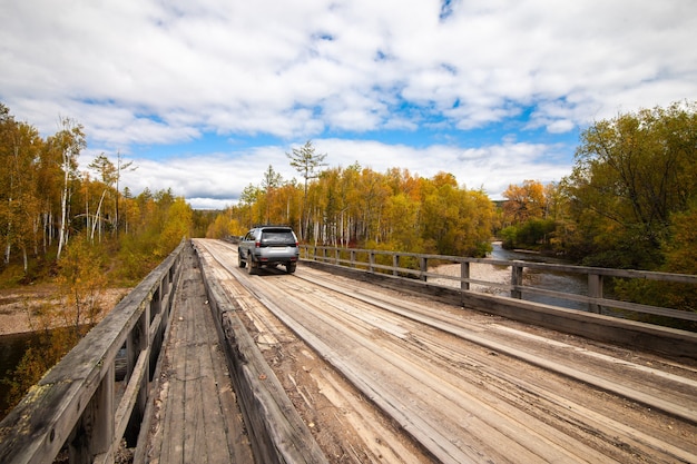 Mitsubishi Pajero Sport on wooden bridge in autumn forest