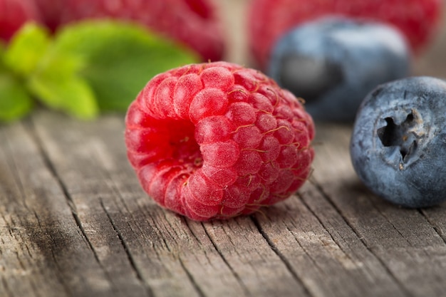 Mix of berries. Raspberries and blueberries on the old a wooden table close-up