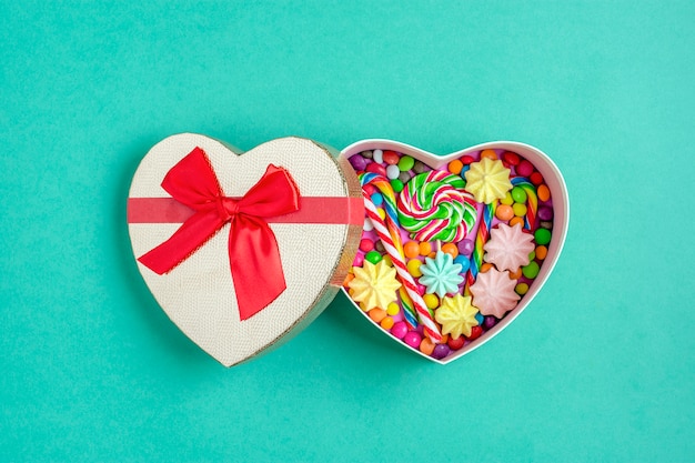 mix chocolate sweets lie in gift box shape of heart on colorful background