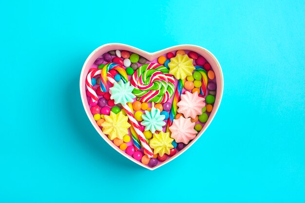 mix  chocolate sweets lie in gift box shape of heart on colorful background