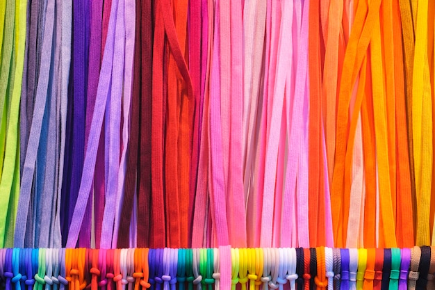 Foto mescolare i panni di tessuti tessili colorati appesi a strisce verticali sul rack trama di tessuti multicolori da vicino