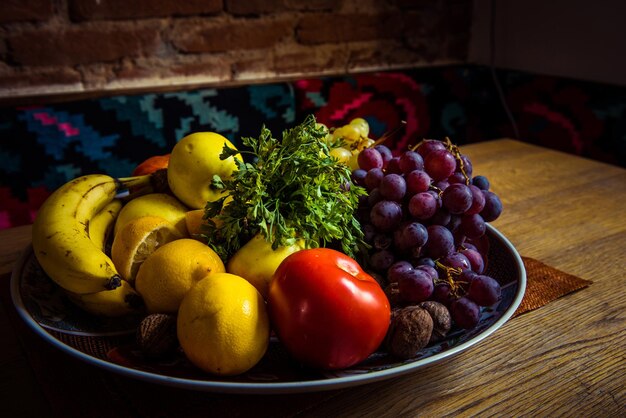 Mix of delicious fruits in a plate on a wooden table