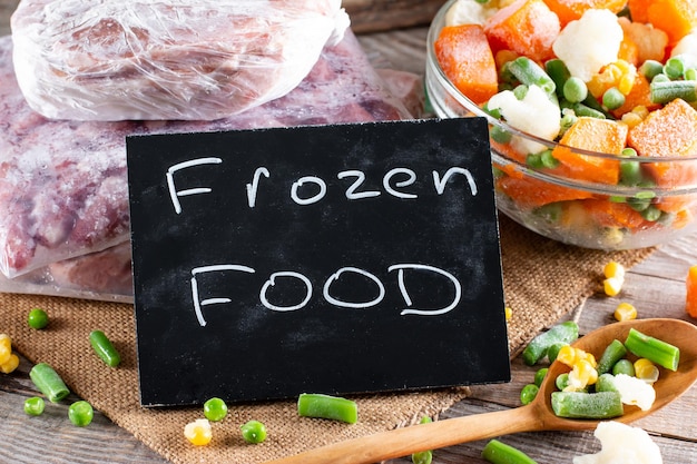 Photo mix of different frozen vegetables on wooden board. frozen food