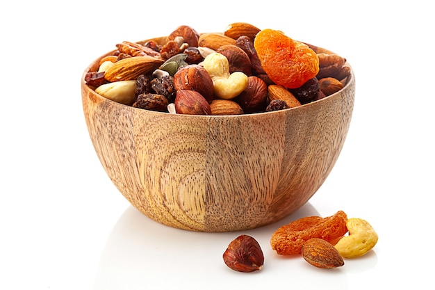 Mix of different nuts and dried fruits in wooden bowl  isolated on white background