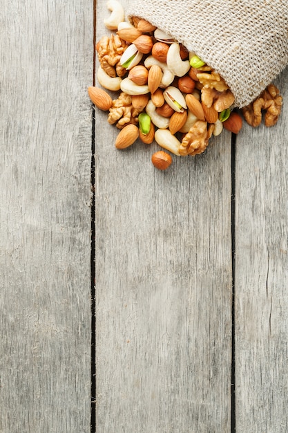 Mix of different nuts in a wooden cup against the background of fabric from burlap