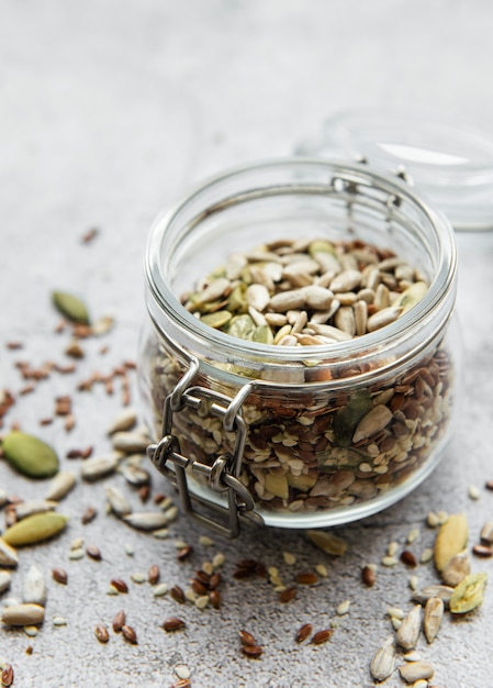 Mix different seeds for a healthy salad, glass jar on a gray concrete desk