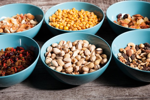 Mix of different type of nuts in bowls on wooden background