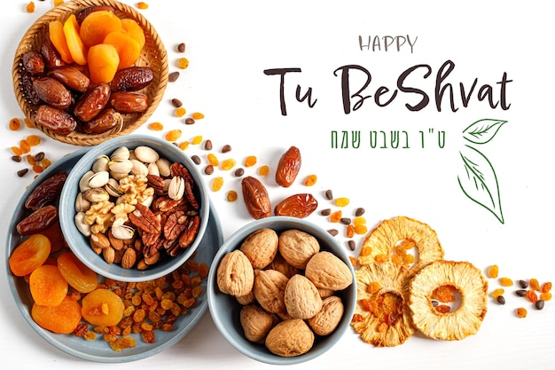 Photo mix of dry fruits and nuts in a wicker plate branch with young green leaves concept of the jewish holiday vertical banner with the inscription tu bishvat in english and hebrew