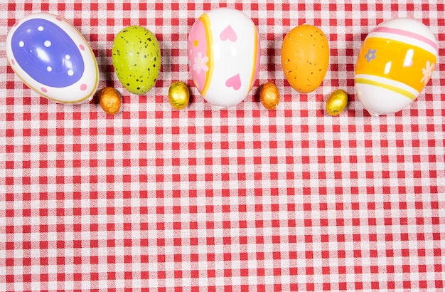 Mix of easter eggs of all colors and sizes on a red and white gingham fabric. Easter concept.