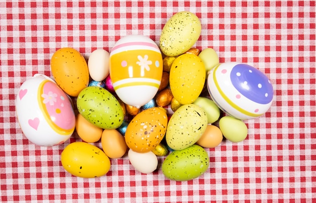 Mix of easter eggs of all colors and sizes on a red and white gingham fabric. easter concept