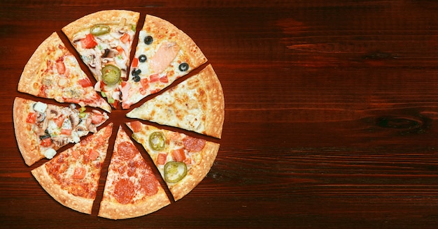 Mix of eight different pizzas on a wooden table  menu concept of choice and diversity