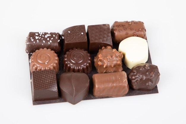 Mix fine dark and milk chocolate in different shapes on presentation cardboard top view in white background