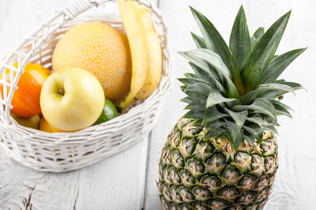 Mix of fresh fruits in the white basket on wooden table