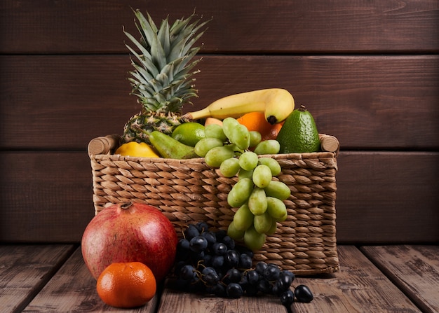 Foto mix di frutta tropicale esotica colorata fresca e succosa in cestino su fondo di legno